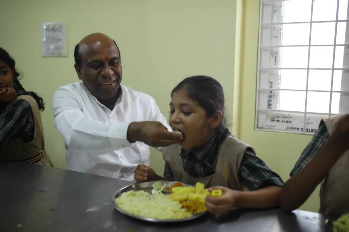 Sri Jadi Madhava Rao feeding a child at lunch